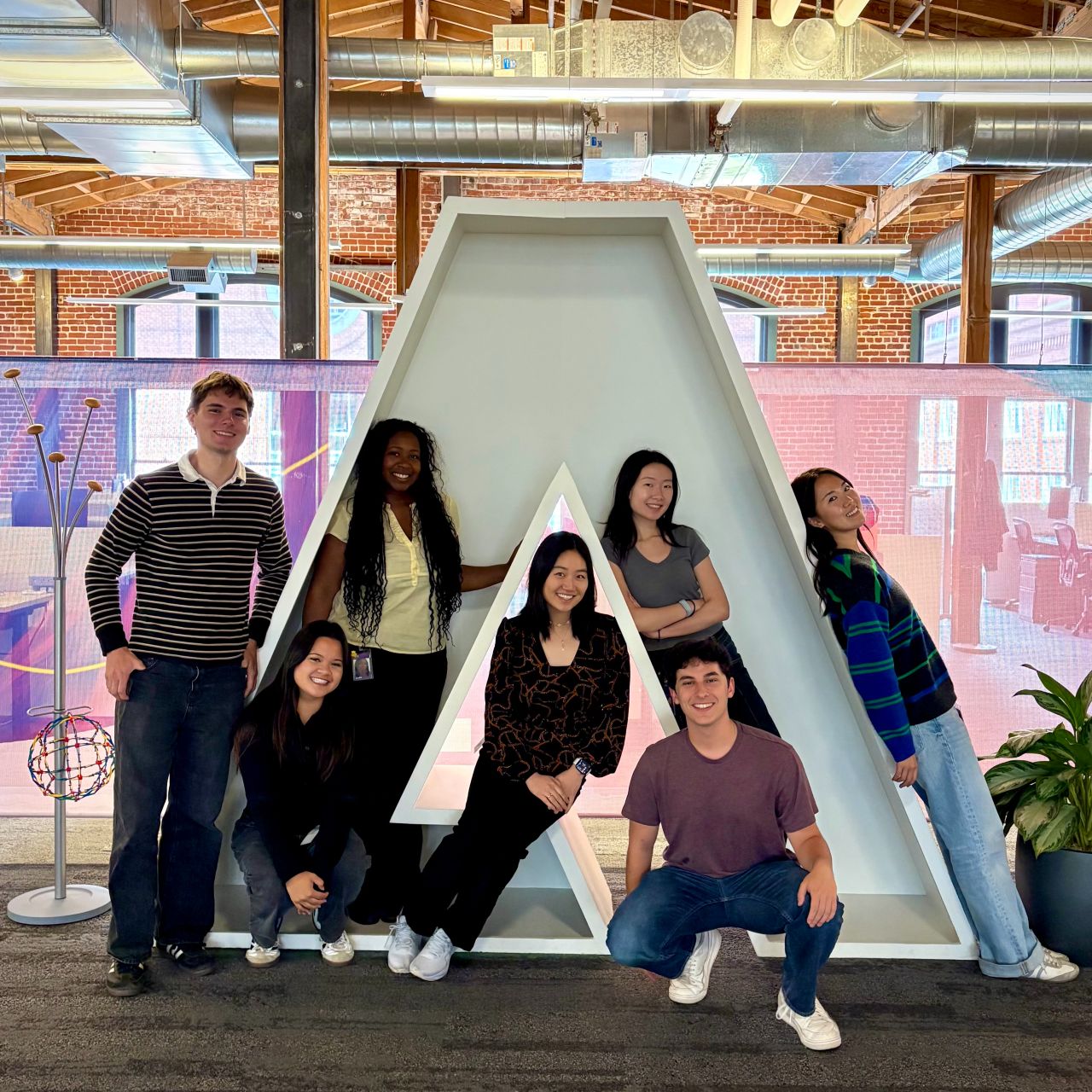 Nishat and fellow interns gathered around an Adobe logo