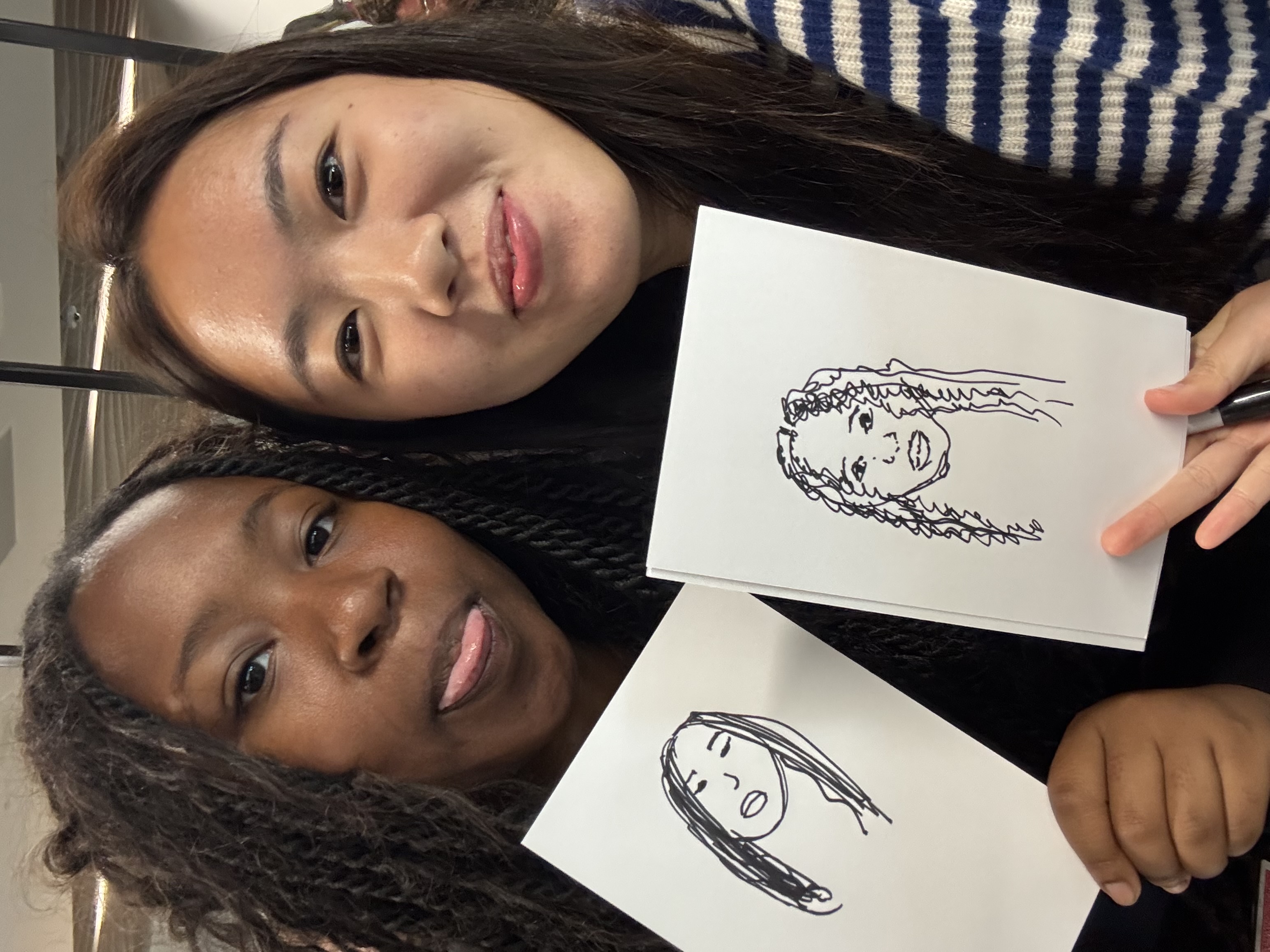 Nishat and a fellow intern holding drawings of each other